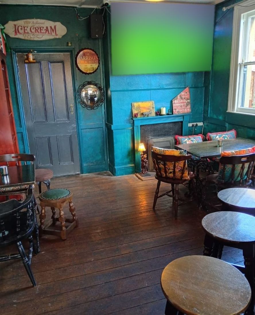 The bar room with its teal walls and big screen, a wooden floor and mismatched chairs with bright cushions.